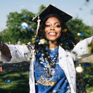 Woman in graduation robes throwing glitter.