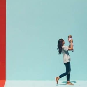 Woman walking and holding a baby up to her face