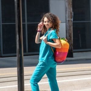 woman in teal scrubs walking on a street